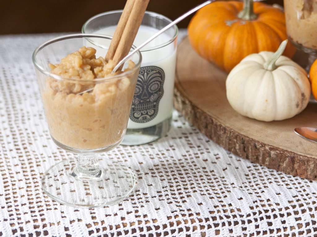 Shot of a glass filled with rice pudding next to a glass of milk with a black etched skull on the front.