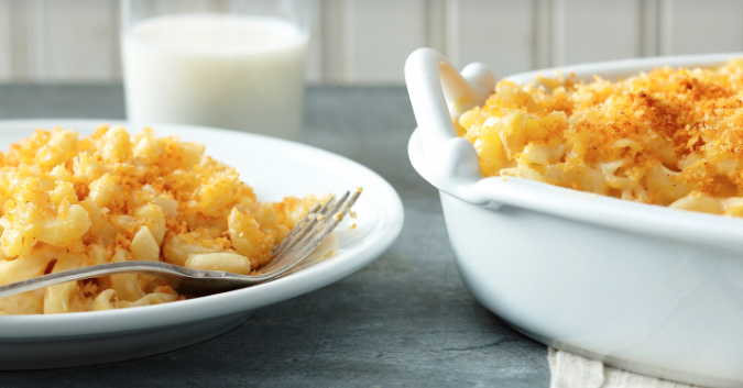 Mac and Cheese with Crispy Crumb topping on a white plate and in a white serving dish. Glass of milk in background.