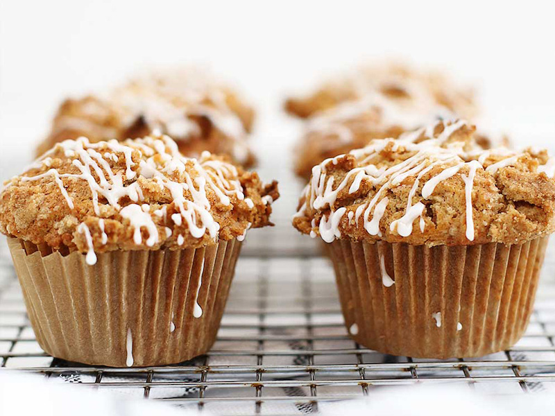 six muffins with crumble topping and drizzled icing