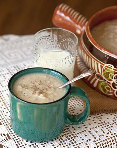 blue mug of oatmeal with a glass of milk and a terra cotta pot in the background