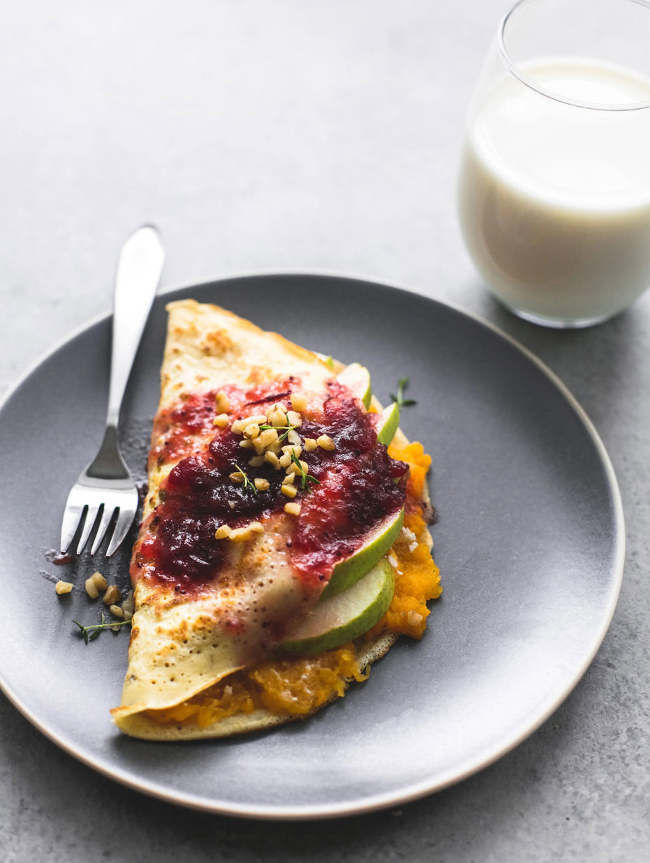 aerial shot of pear and squash crepe on a gray plate with a glass of milk on the side.