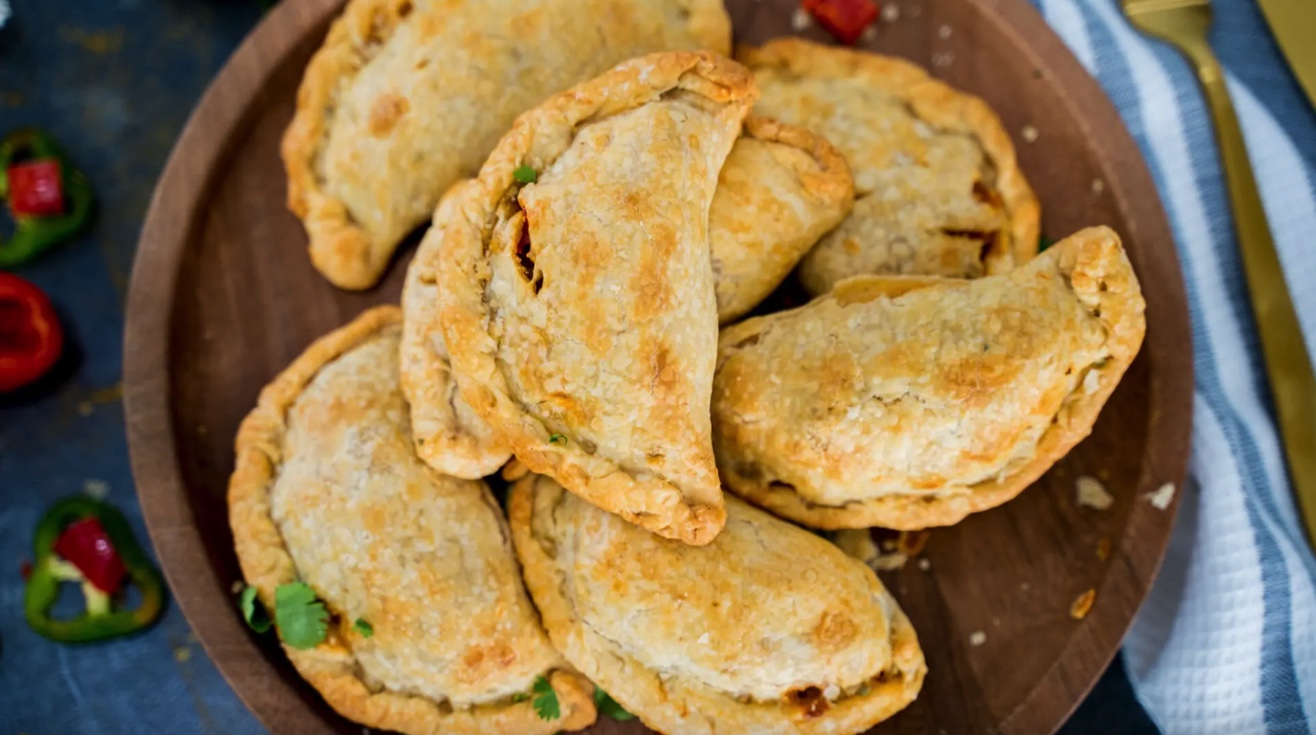 doughy empanadas on wood plate