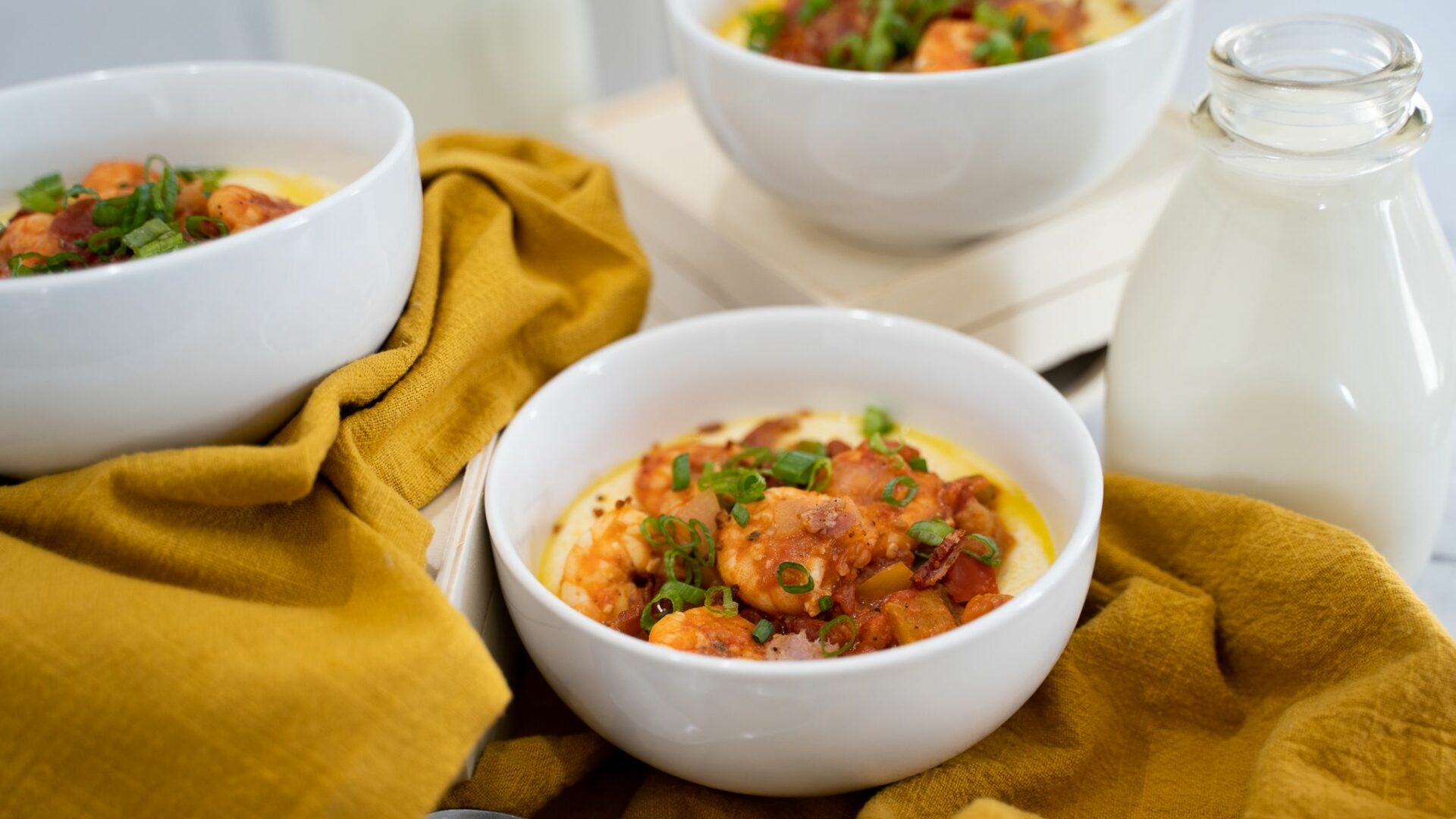 shrimp and grits in a white bowl on yellow table cloth