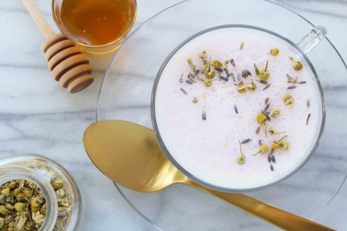 purple tea with loose lavender on top with a side of honey and additional lavender and a gold spoon