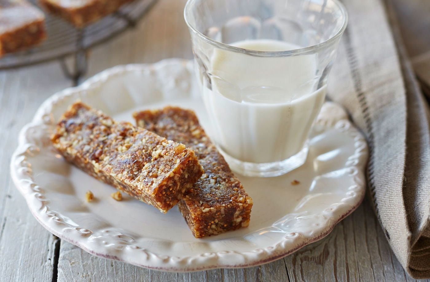 granola bars on a white plate with a glass of milk